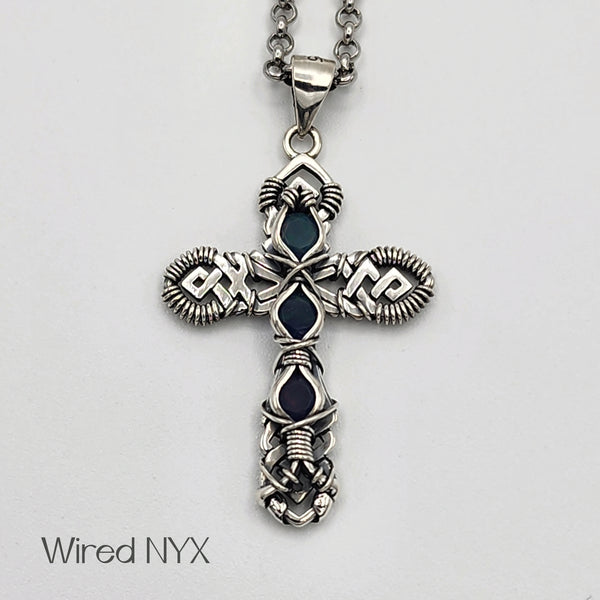 Black Opal Gemstone Wire Wrapped Cross Pendant in Sterling Silver (Oxidized) Material: Sterling Silver (Oxidized) Stones: Black Opal Pendant height: 36mm Pendant width: 23mm Chain: Stainless Steel Round Rolo Chain (3mm) ~ Choose Length 18"-30" Inches