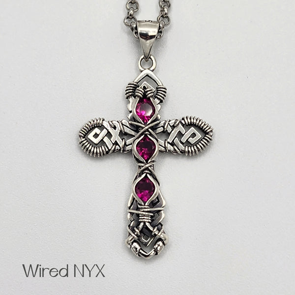 Ruby (Lab Created) Wire Wrapped Cross Pendant in Sterling Silver (Oxidized) Material: Sterling Silver (Oxidized) Stones: Ruby (Lab Created) Pendant height: 36mm Pendant width: 23mm Chain: Stainless Steel Round Rolo Chain (3mm) ~ Choose Length 18"-30" Inches